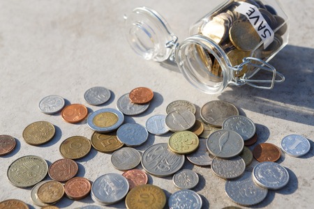 Coins mix fall out of glass jar with label save on floor, copy space. Saving money, economic crisis...