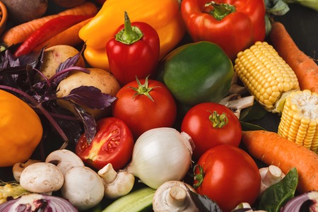 Fresh organic vegetables on wood background. Healthy natural food on rustic wooden table. Tomatoes, garlic, mushrooms, corn, basil, bell pepper and other cooking ingredients. Grocery store conceptの写真素材