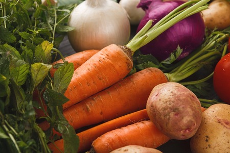 Fresh organic vegetables on wood background. Healthy natural food on rustic wooden table. Carrot, garlic, potato, onion and herbs. Grocery store conceptの写真素材