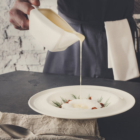 Waiter pouring broth to mushroom cream soup. Original restaurant serving of delicacy meal, copy spaceの写真素材