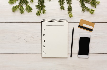 Christmas online shopping. Smartphone, credit card and wishlist with copy space on white wooden...