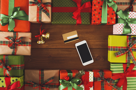 Preparing for holidays background. Gift boxes frame, mobile and credit card on wood. Seasonal sales, online shopping, presents for any holiday concept. Top view, flat lay, copy spaceの写真素材