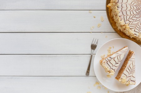 Esterhazy cake sliced on white plate top view. Delicatessen sweet dessert with almond meringue dough...