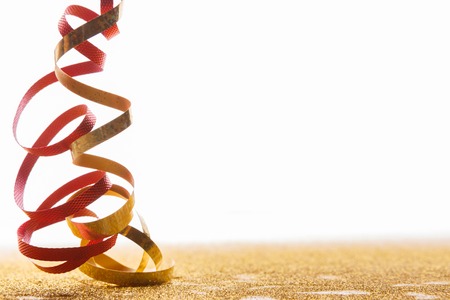 Curly red and golden serpentine on white background, copy space. Christmas and new year holiday concept. Bright luxury celebration backdropの写真素材