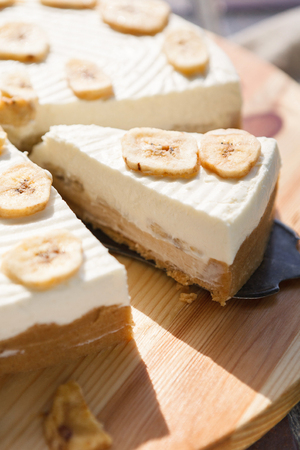 Delicious banana cake on table. Sliced fruit biscuit with caramel and buttercream on wooden catering plate, copy spaceの写真素材