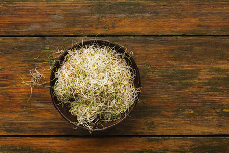 Mixed micro greens bowl at wooden background. Eating right and cooking ingredients concept. Fresh...