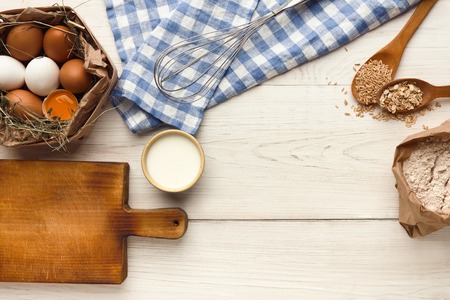 Cooking ingredients for homemade oatmeal cookies. Oat flakes, eggs and milk at white rustic background with copy space, top view. Handmade pasty concept and recipe mockupの写真素材