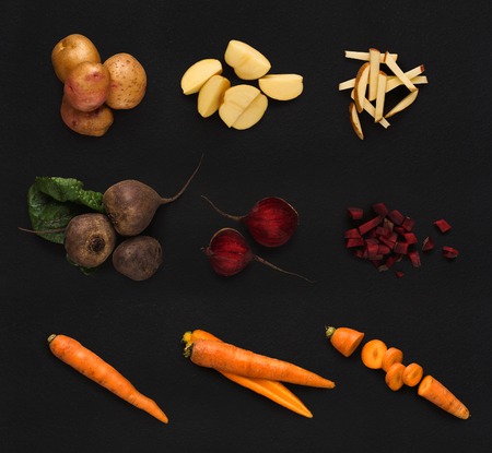 Set of vegetables isolated on black background. Whole and cut cooking ingredients for sald or soup. Vegetarian food, vitamins and eating right concept, top view. Potato, beetroot, carrotの写真素材