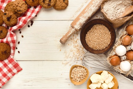 Cooking ingredients for sweet oatmeal cookies background. Eggs, butter, flour, spices and kitchen utensils on white wood. Recipe or baking classes mockup, pastry making concept, top view, copy spaceの写真素材
