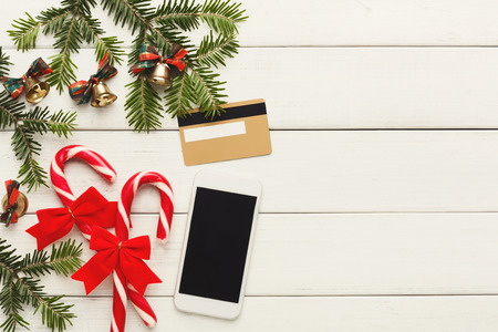 Preparing for winter holidays background. Smartphone, credit card and christmas decorations on white...