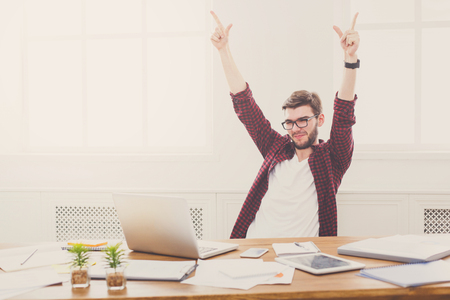 Young successful businessman celebrate in office with computer. Job in internet.の写真素材