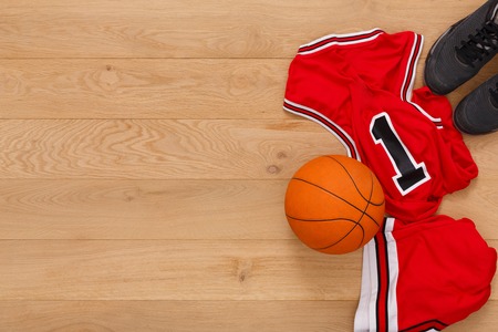 Basketball player outfit background top view, copy space. Professional uniform, ball and sneakers on parquet floorの写真素材