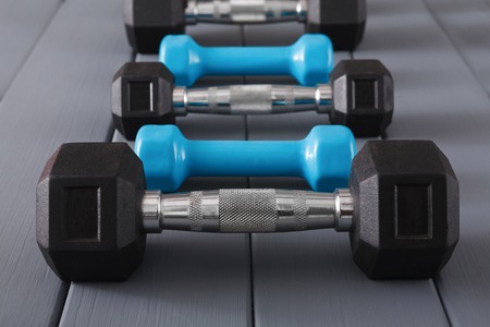 Dumbbells set on grey wooden background. Weight exercise, powerlifting, bodybuilding conceptの写真素材