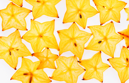 Backlit carambola fruit slices isolated on white background. Closeup of cut exotic fruit, pattern and texture, top viewの写真素材
