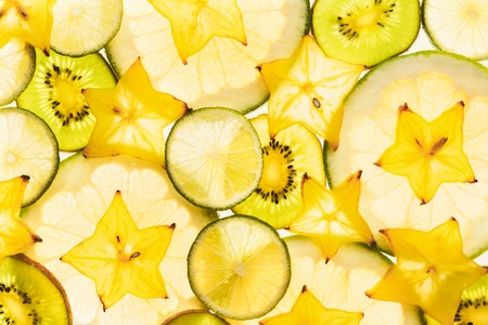 Backlit citrus fruits slices. Abstract green and yellow background with cut lime, lemon, pomelo,...