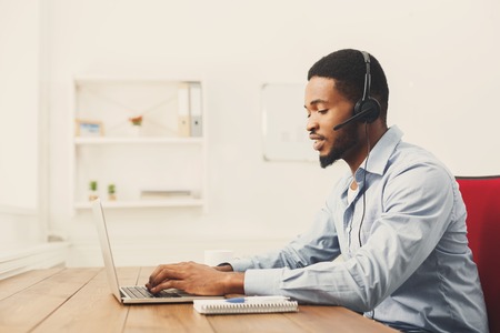 Call center operator with headset. African-american man working in support service or hotline in...