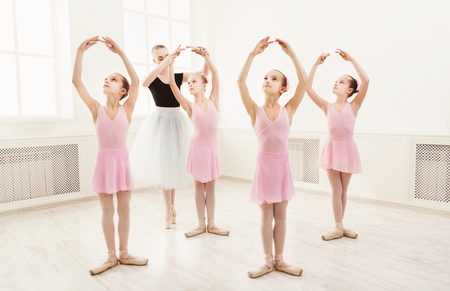 Young ballet teacher and students ballerinas in dance class. Girls are engaged in choreography in the ballet school.の写真素材