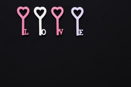 Happy Valentines Day with heart in keys form pastel pink and violet decorations, copy space on black...
