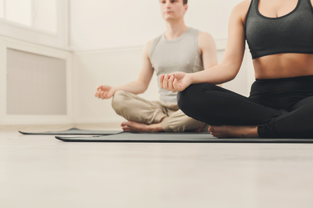 Young couple meditating together. Unrecognizable man and woman sitting near in lotus pose on mat, copy spaceの写真素材