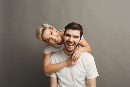 Happy man carrying his girlfriend on back. Young couple having fun togetherの写真素材