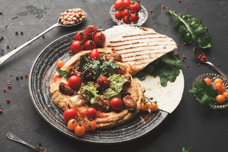 Chickpea hummus with mussels and vegetables in stylish bowl. Healthy traditional vegetarian beans pasta with olive oil and fresh pita bread served on black table background, copy spaceの写真素材