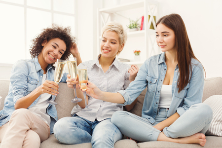 Three friends toasting with champagne glasses. Young happy women cheering with sparkling wine, chatting and celebrating, slumber party, copy spaceの写真素材