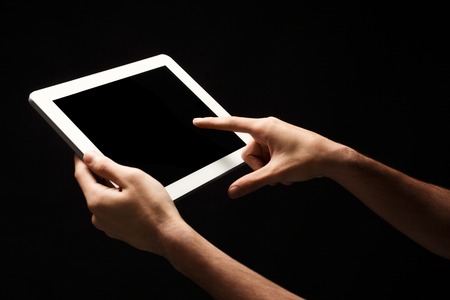 Male hands holding and pointing to blank screen of digital tablet. Caucasian man using device with...