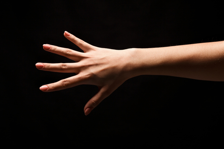 Female hand showing back side of open palm, number five isolated at black background. Counting, gesturing, enumeration concept, cutout, copy spaceの写真素材