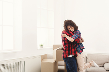 Happy african-american couple embracing at new home among moving boxes, copy space.の写真素材