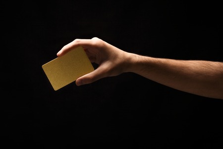 Ð¬ale hand holding blank plastic credit card or business card on black isolated studio background. Banking services and acquaintance concept, copy space, cutout, low keyの写真素材