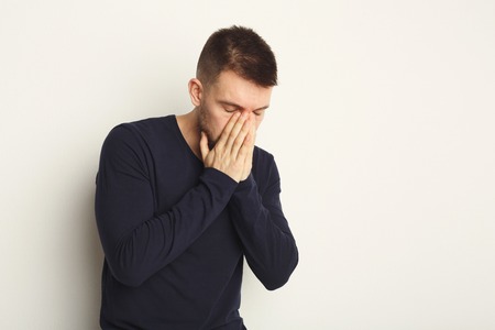 Upset man with closed eyes posing in studio. Fashion boy on white background, studio shot, copy...