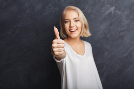 Happy young woman giving thumb up gesture. Smiling woman approve and recommend. Victory, luck, success conceptの写真素材