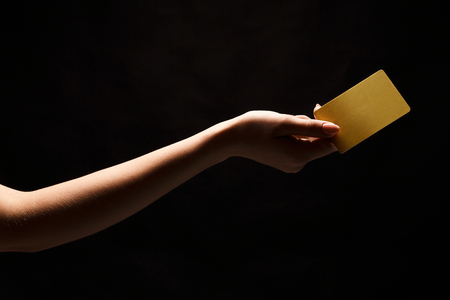 Female hand holding blank plastic credit card or business card on black isolated studio background. Banking services and acquaintance concept, copy space, cutout, low keyの写真素材