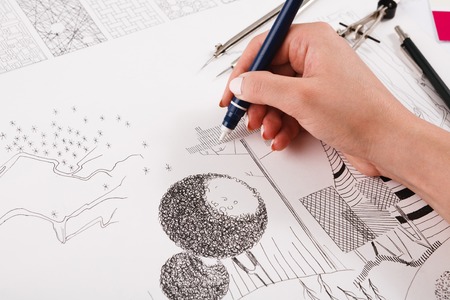 Architect drawing architectural project closeup. Unrecognizable designer hands working with building blueprint, copy spaceの写真素材
