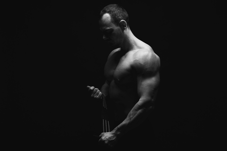 Strong athletic man, bodybuilder. Naked torso, muscular body. Strong chest and shoulder muscles. Studio shot on black background, low key. Bodybuilding concept, black and white imageの写真素材
