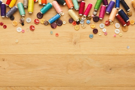 Creative sewing background, top view. Collection of various buttons, threads and pins arranged as a...
