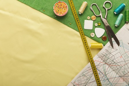 Fashion designer workspace top view. Sheets of professional sewing patterns, measuring tape, chalk...