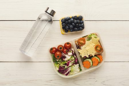 Healthy food concept. Lunch box filled with mixed vegetables, sandwich, blueberries and water bottle...