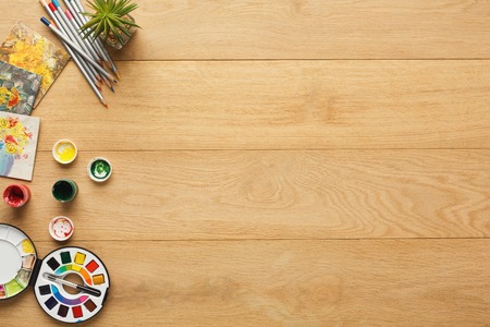 Border of various stationery for art, top view. Light wooden desktop with pencils, different colors. Studying and creative background, copy spaceの写真素材