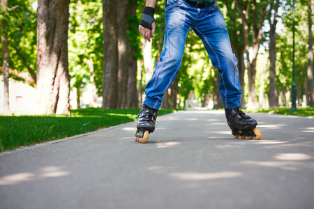 Male legs in blue jeans and roller skates. Man enjoying sports outdoors. Active and healthy lifestyle background, copy spaceの写真素材