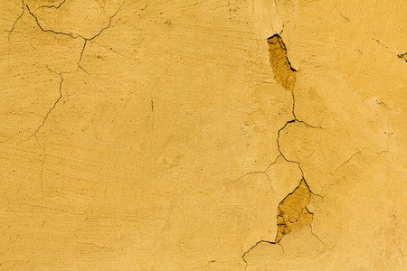 Rustic chapped painted wall texture abstract background. Shabby surface of yellow wall with cracks, textured backdrop with copy spaceの写真素材