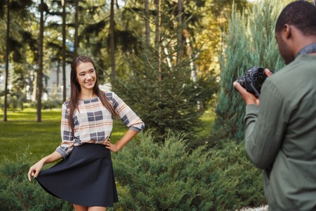 Multiethnic couple in love taking pictures on camera. Asian woman posing for her african-american boyfriend in park, copy spaceの写真素材