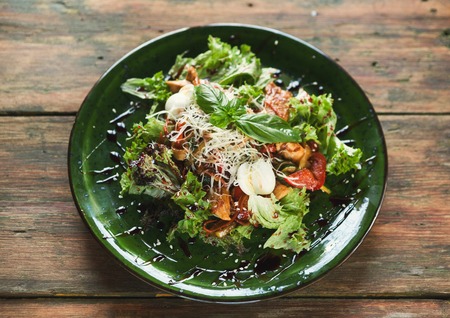 Caesar salad with quail eggs and chicken meat. Fresh side dish with vegetables on wooden table, restaurant serving, top viewの写真素材