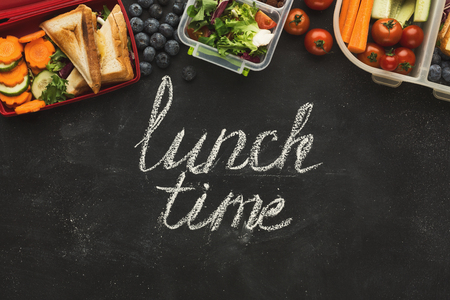 Eating right, storage and dieting conceptual background. Assortment of healthy food in plastic containers on black chalk board with lunch time inscription and copy space, top viewの写真素材