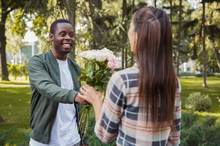Man giving flowers for his beautiful girlfriend, having anniversary date in park, copy spaceの写真素材