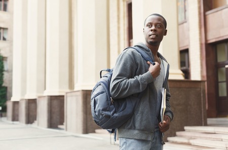 Pensive african-american student with books outdoors, looking away, dreaming or thinking during break, having rest in campus. Education concept, copy spaceの写真素材
