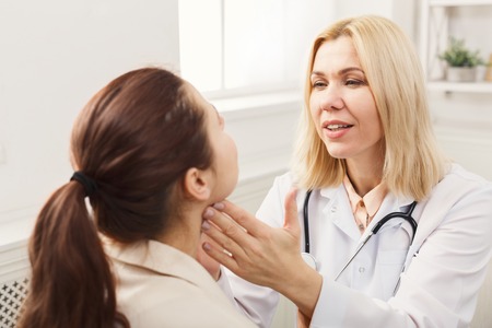 Female doctor with stethoscope checking patient neck at hospital. Medicine, healthcare and people conceptの写真素材