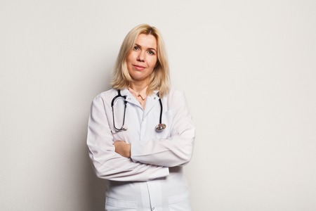 Attractive woman pharmacist with crossed arms on white background. Medicine, healthcare and medical equipment concept, copy spaceの写真素材