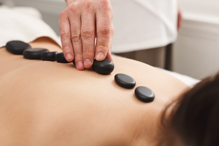 Beautiful woman getting hot stones back massage in spa salon. Beauty treatment therapy, wellness and relaxation conceptの写真素材