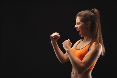 Emotional female fighter ready to fight over black background. Kickboxing and fight sport concept. Studio shot, low key, copy spaceの写真素材